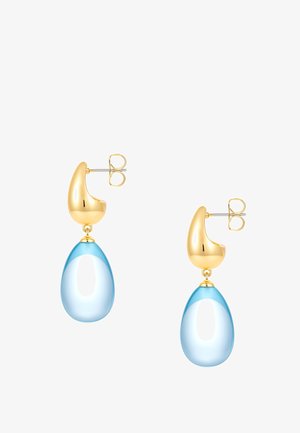 Boucles d'oreilles clous couleur or avec des formes lisses et irrégulières tenant des pendentifs translucides en forme de goutte bleue.