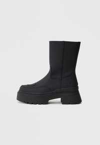 Melni potīšu zābaki ar masīvu platformas zoli, izgatavoti no gludas sintētiskas materiāla. Šiem zābakiem ir izšuvumi un logo sānos.