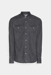 Tummansininen napillinen paita pitkillä hihoilla, terävä kaulus, kaksi rintataskua ja kontrastiväriset ompeleet. Varustettu hopeisilla napeilla ja kaarevalla helmapäällä.