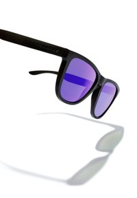 Black sunglasses with thick frames and purple lenses. Features a side engraved logo. Clear shadow projected on a white background.