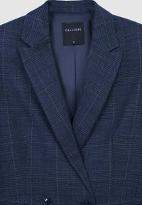 Blazer a quadri blu navy con rever strutturati e chiusura a doppio bottone. Realizzato in tessuto testurizzato, presenta un'etichetta con la scritta "CALLIOPE" e taglia S.