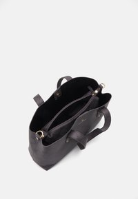 Bolsa tote negra hecha de material texturizado con un patrón sutil, que cuenta con dos asas, un bolsillo interno con cremallera y herrajes en tono dorado.