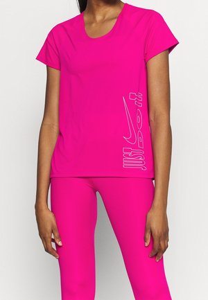 Frau trägt hellpinkes, kurzärmeliges Sportshirt und passende Leggings mit weißem Nike "Just Do It" Logo an der Seite des Shirts.