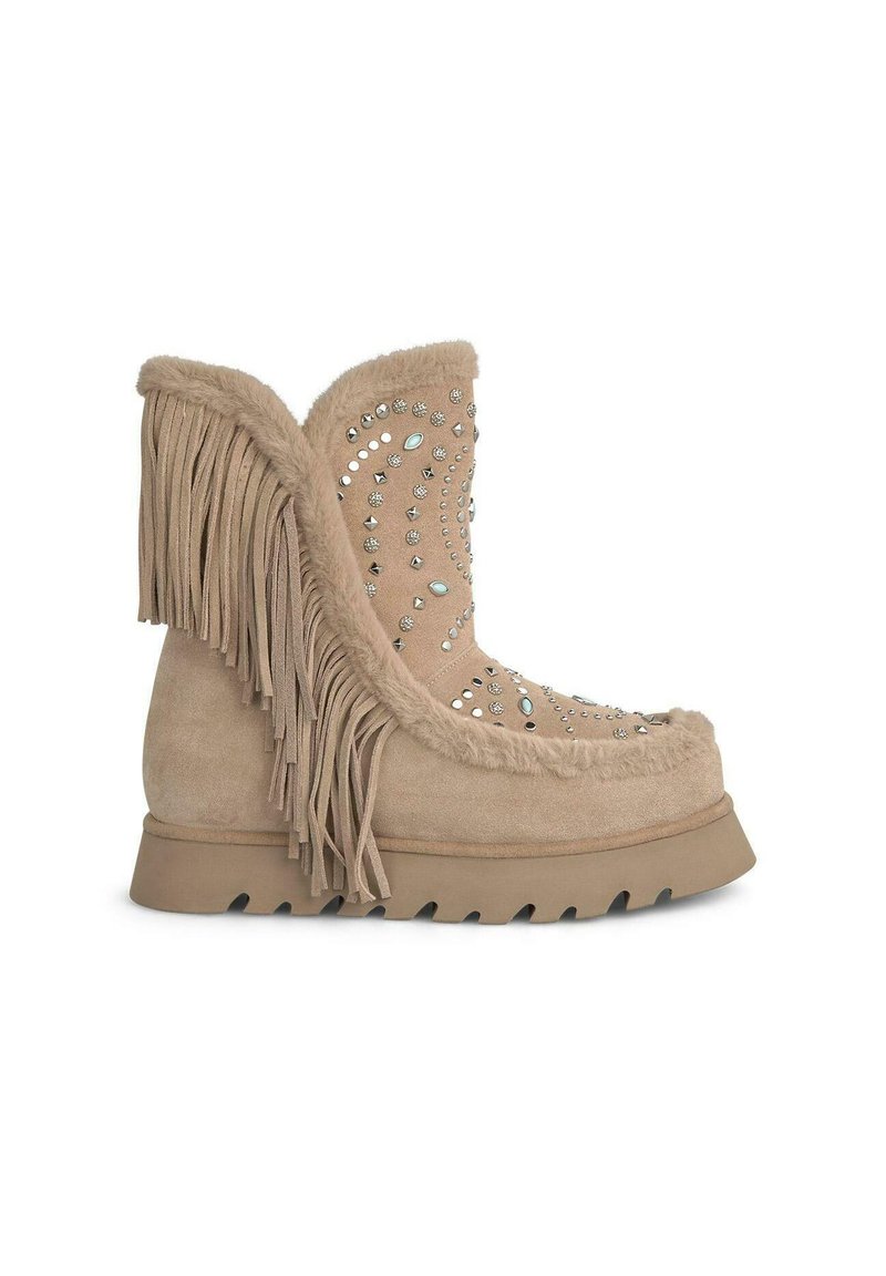 Beige Wildleder-Stiefelette mit Fransenverzierung, verziert mit silbernen Nieten, ausgestattet mit einer strukturierten Sohle für Halt und einem weichen Fellfutter.