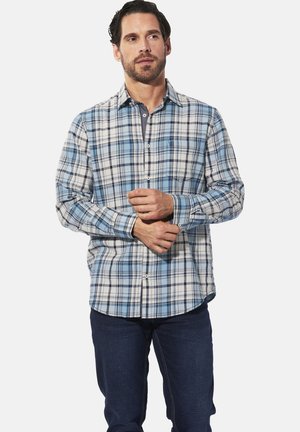 Blau-weißer karierter Langarmhemd mit Button-Down-Kragen, ausgestattet mit einer Brusttasche und einem abgerundeten Saum, kombiniert mit dunklen Jeans.