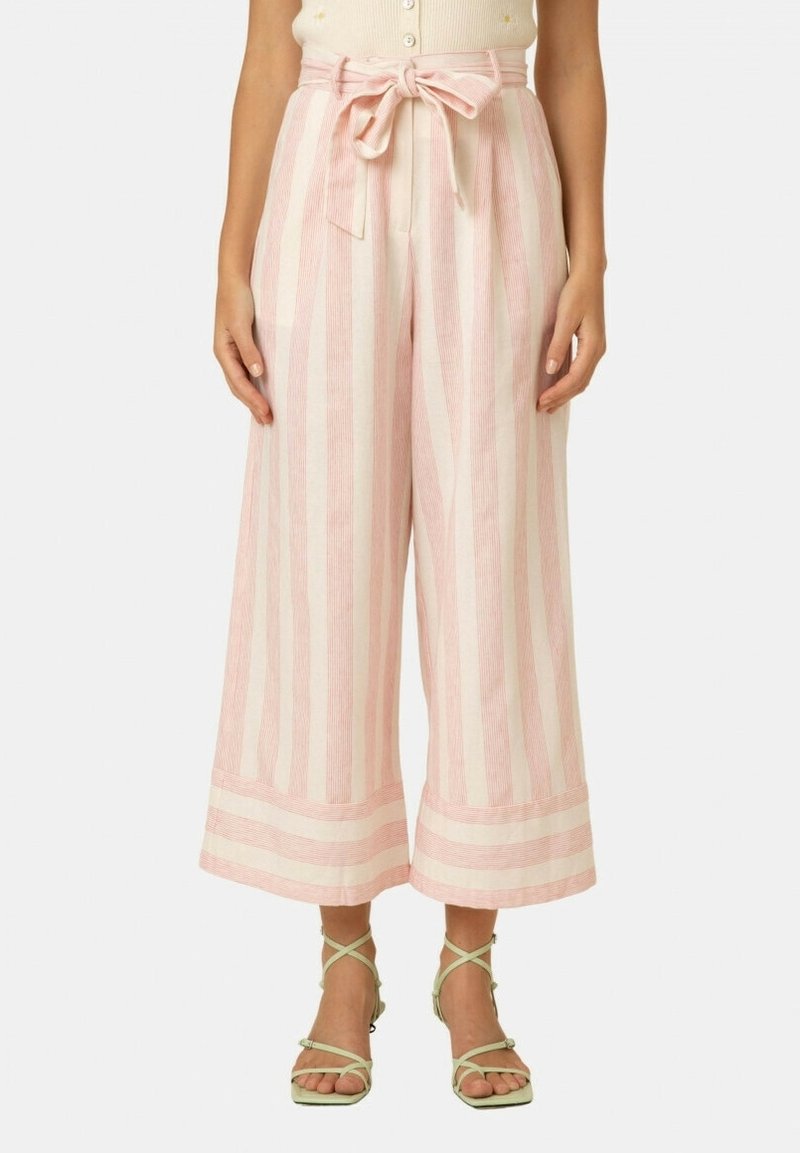 Pantalon à jambes larges rayé verticalement rose et crème avec ceinture nouée à la taille, porté avec un haut crème et des talons légers à brides vert clair.