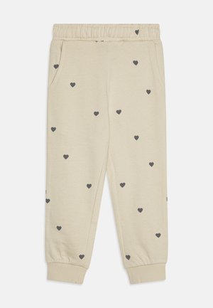 Pantaloni sportivi beige con vita elastica, caratterizzati da una stampa di cuori grigi scuri distribuiti in modo casuale, due tasche laterali e polsini a costine.