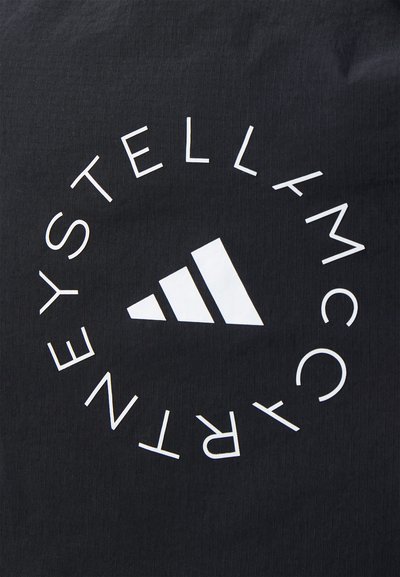Melna auduma ar vertikālu tekstūru, kurā redzams balts apļveida logo un teksts. Logo centrā ietver stilizētu trīsstūra formu.