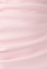 Soft pink fabric with subtle wavy texture and gentle folds creating a smooth, flowing surface.