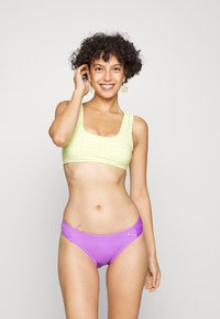 Gul rutete bikini topp med firkantet utringning og brede stropper, kombinert med lilla bikini underdeler med siderekken og en liten logo detalj.
