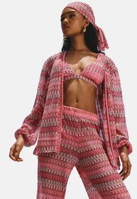 Roze gepatroneerde driekleurige outfit met een cropped top, een lange mouwen cardigan met gerimpelde manchetten en bijpassende broeken.