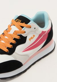 Colorful sneaker featuring white synthetic leather, black suede accents, orange laces, pink and blue highlights, and a textured outsole.