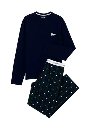 Granatowa koszula z długim rękawem z białym logo krokodyla w połączeniu z ciemnozielonymi i niebieskimi spodniami w kratę, na których znajdują się białe nadruki krokodyli oraz branding Lacoste.