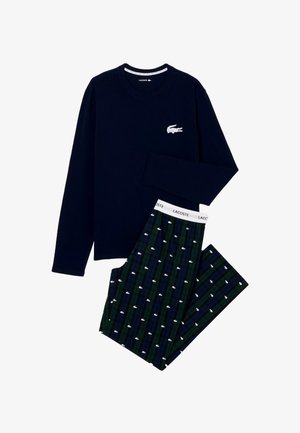Granatowa koszula z długim rękawem z białym logo krokodyla w połączeniu z ciemnozielonymi i niebieskimi spodniami w kratę, na których znajdują się białe nadruki krokodyli oraz branding Lacoste.