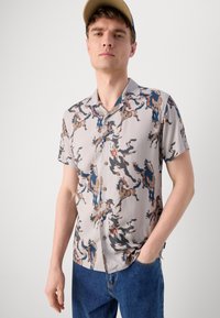 Short-sleeved, button-up shirt in light gray with a colorful animal print design. Made from lightweight fabric with a smooth texture.