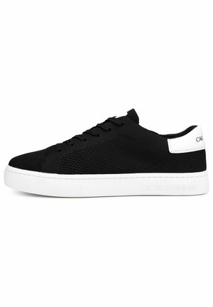 Schwarzer Low-Top-Sneaker mit weißer Sohle und Fersenlasche, gestricktem Obermaterial, Schnürsenkeln und "Calvin Klein Jeans" Branding auf der Sohle und Ferse.