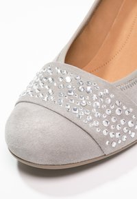Ballerines en suède gris avec un bout rond, ornées de bijoux sur le dessus pour un détail supplémentaire. Doublure intérieure lisse.