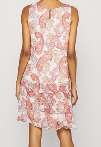 Ærmeløs kjole i let stof med et paisley-mønster i pink og guld. Inkluderer en nøglehuldetalje bagpå og lagdelt kant.