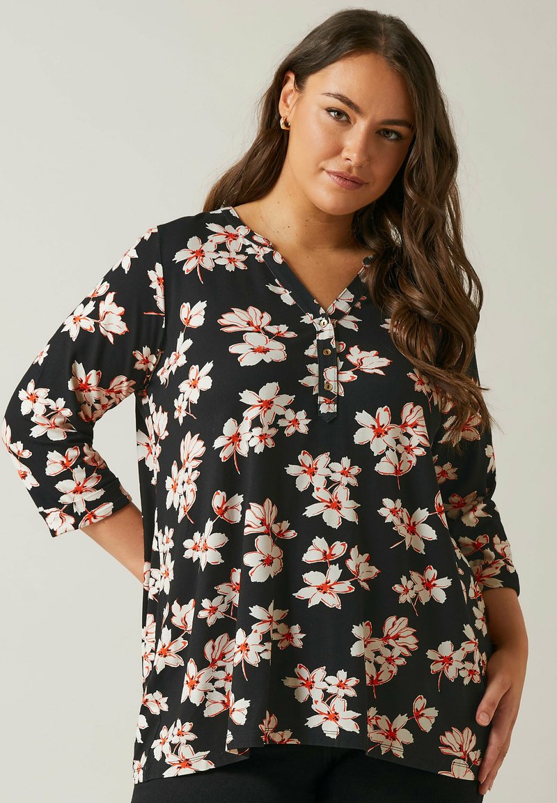 Tunic nera floreale con maniche 3/4, caratterizzata da fiori bianchi e rossi, scollatura a V e dettaglio con bottoni al collo. Tessuto morbido con una vestibilità comoda.