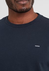 Navy cotton t-shirt with a round neckline and a small TOG24 logo sewn on the front, featuring a smooth texture and short sleeves.