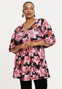 Bloemige tuniek met een zwarte basis en grote roze bloemen, een V-halslijn en wijde mouwen, vervaardigd uit lichte stof.