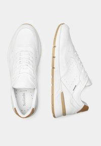 Hvide sneakers med en glat læderoverdel, perforerede detaljer, rund tå og en beige gummisål. Indeholder snørebånd og bagakcenter.