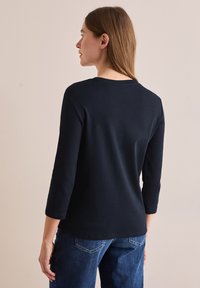 Marintröja i m�örkblått med lång ärm i mjukt material och rund halsringning. Ser avslappnad ut med en enkel design.