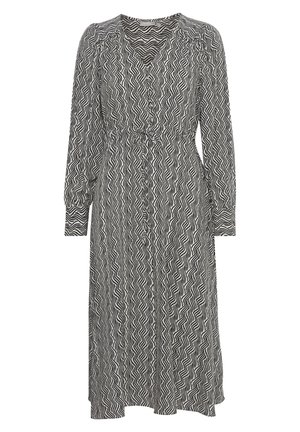 Black and white patterned dress with a v-neck, long sleeves, and a cinched waist. Features a wavy design and a relaxed fit.