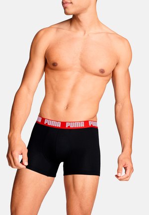 Schwarze Boxer-Shorts mit einem roten Puma-Logo auf dem elastischen Bund. Das Material wirkt glatt und dehnbar, für Komfort und Passform entworfen.