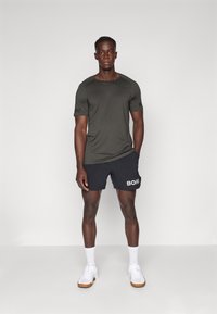 Conjunto atlético composto por uma camisa de mangas curtas verde escura com detalhes pretos e calções pretos, ambos com a inscrição "BORG" em branco.