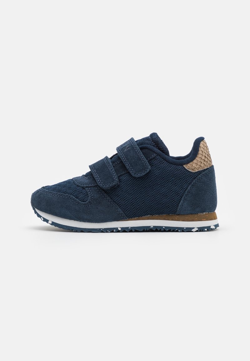 Baskets enfant bleu marine avec double fermeture velcro, dessus en mesh et suède, patch de talon marron texturé et semelle en caoutchouc blanche.
