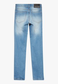 Jeans de mezclilla azul claro con un diseño de pierna recta, con un lavado deslavado, costuras naranjas y una etiqueta negra en la cinturilla.