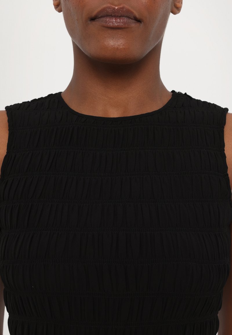 Czarna sukienka z pionowym marszczeniem, okrągłym dekoltem i bez rękawów. Materiał wydaje się lekki i elastyczny.