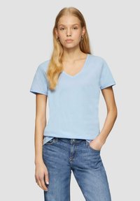 T-shirt di cotone azzurro chiaro con scollo a V, maniche corte e vestibilità rilassata. Abbinato a jeans in denim blu, per un look casual.