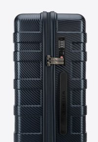 Hartschalenkoffer in Marineblau mit einer Karbonfaserstruktur, horizontalen Rillen, doppelten Reißverschlüssen, integriertem Zahlenschloss und markanten Akzenten.