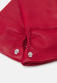 Red leather gloves featuring silver skull accents and decorative stitching at the wrist, showcasing a smooth texture and fitted design.
