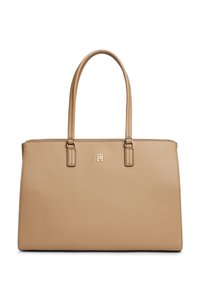 Μπεζ δερμάτινη τσάντα χειρός με δύο λουριά και ένα μικρό μεταλλικό λογότυπο στο κέντρο κάτω από τα λουριά.