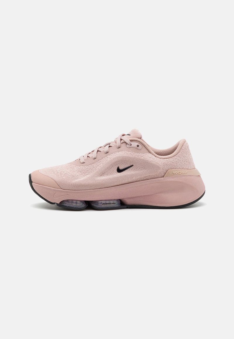 Ljusrosa Nike-sneakers med en texturerad mesh-övre, svart swoosh-logotyp och synlig dämpning i sulan, med en rundad tådesign.