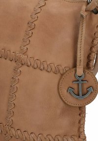 Bruine leren handtas met gevlochten stiksels, een ronde ankerhanger en een zachte textuur. Compakte vormgeving met een gestructureerde silhouet.