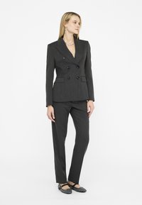 Blazer doppiopetto grigio a righe fini e pantaloni abbinati. L'outfit presenta spalle strutturate e design a gamba dritta con tasche.