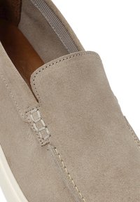 Suede slip-on shoe in light beige with a smooth texture, featuring discreet stitching and a rounded toe. Interior lining is brown leather.