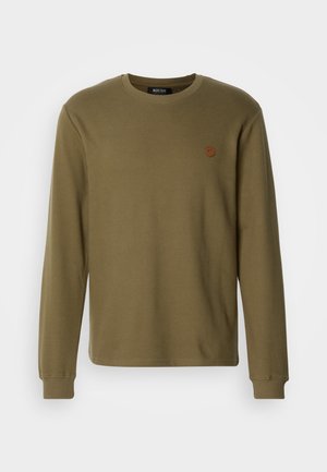 Olive green long-sleeve crew neck shirt with ribbed cuffs and a small round brown logo patch on the left chest.