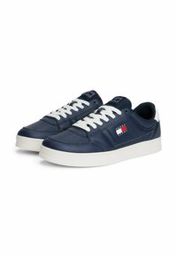 Granatowe skórzane sneakersy z białymi sznurówkami i podeszwą. Posiadają czerwono-białą łatę z logo z boku oraz perforacje w obszarze palców.