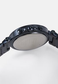 Reloj de acero inoxidable negro con una caja redonda, que presenta un bisel texturizado, múltiples botones en el lateral y un fondo pulido.