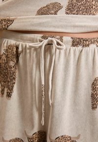 Licht beige loungewear set met schattige prints van hooglandrunderen. De broek heeft een elastische tailleband met een stijlvolle trekkoord. Zachte textuur.