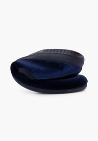 Zapatilla de color azul marino con parte superior de suave terciopelo, diseño curvado, textura acolchada y suela de goma flexible con patrones de agarre elevados.