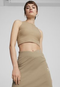 Tan ribbet crop top med høj krave, parret med en matchende nederdel med plisseret design og guld logo accent. Glat tekstur.