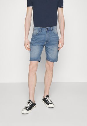 Shorts din denim de culoare albastră deschisă, cu croi drept, design cu cinci buzunare și închidere cu nasture. Purtați cu adidași din pânză negri.
