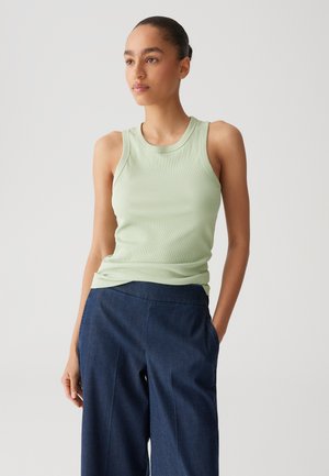 Light green ribbed tank top with a round neckline and wide shoulder straps, paired with dark blue wide-leg trousers.