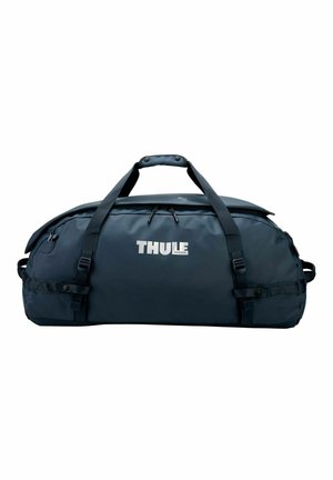 Grand sac polochon Thule bleu foncé avec double sangle de transport et compartiment principal zippé sur fond blanc.